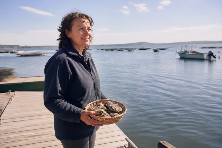 Productrice locale à Bouzigues présentant ses huîtres fraîchement récoltées sur le port.