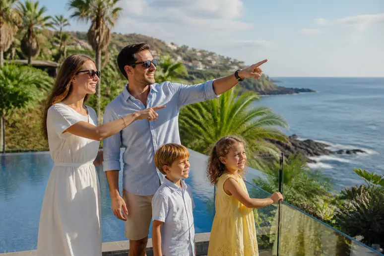 Famille souriante profitant de la piscine d'un hotel madere avec vue sur l'océan.