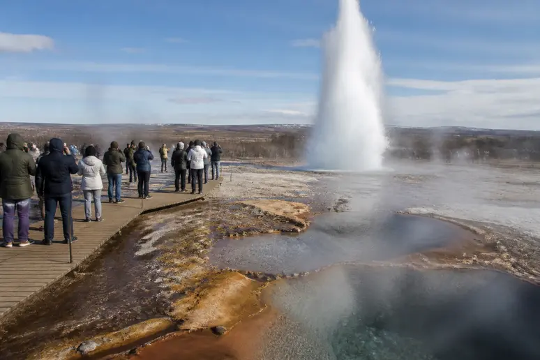 Un groupe de touristes observe l'éruption du geyser Strokkur sur le site de Geysir, islande cercle d'or.