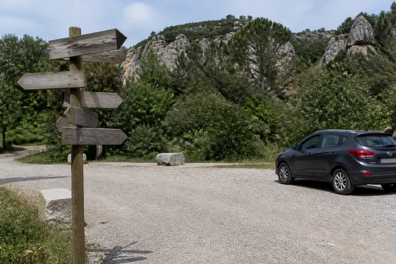 Panneaux de signalisation en bois indiquant les sentiers et le parking près de la cascade de Glandieu