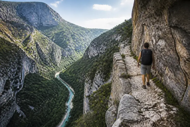 Randonneur marchant sur le sentier des corniches surplombant les gorges de la jonte