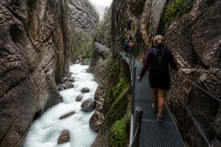 Promeneurs marchant sur la passerelle sécurisée surplombant les gorges creusées par la rivière