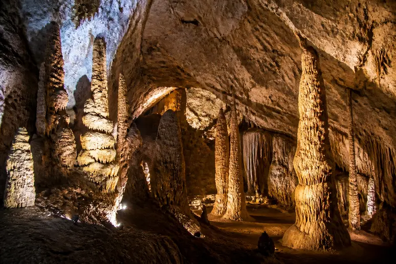 Immense salle souterraine illuminée remplie de stalagmites monumentales dans les gorges du tarn