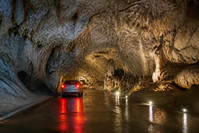 Voiture circulant à faible allure sous la voûte rocheuse de la grotte du Mas-d'Azil