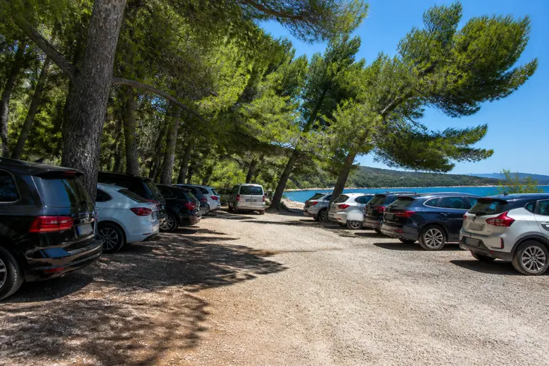 Véhicules stationnés sur le parking gratuit près de la plage de Cupabia sous les pins