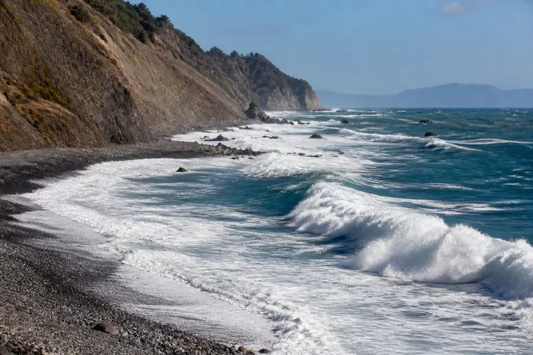 Vagues puissantes s'écrasant sur la pente abrupte des galets noirs de la plage de Nonza